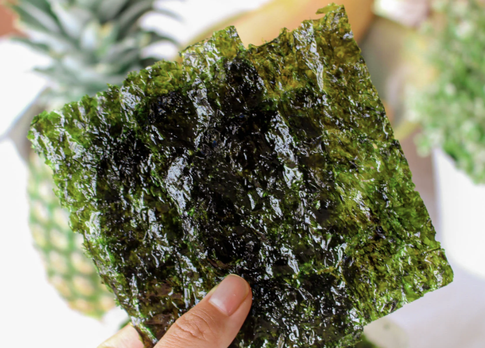 Crispy roasted Korean seasoned laver sheets held in hand